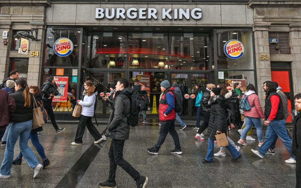 People with coats walking past a Burger King restaurant.