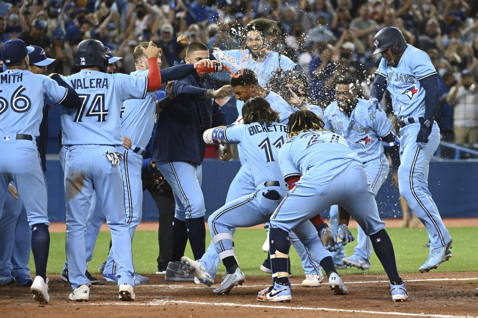 Toronto Blue Jays' Marcus Semien, center, celebrates with teammates after hitting a three-run walkoff home run against the Oakland Athletics in the ninth inning of a baseball game in Toronto, Friday, Sept. 3, 2021. (Jon Blacker/The Canadian Press via AP)