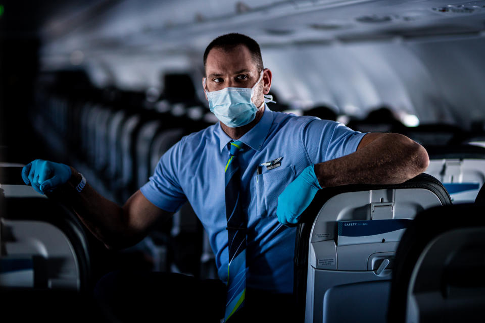 A flight attendant on an empty flight staying safe with a mask.