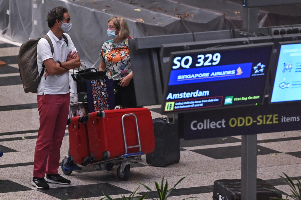 Passengers arriving from Amsterdam get their bags at Changi Airport in Singapore on October 20, 2021, a day after the country began quarantine-free entry for fully vaccinated passengers from eight countries, part of a plan to ease restrictions as the business hub gears up to live with the coronavirus. (Photo by Roslan RAHMAN / AFP) (Photo by ROSLAN RAHMAN/AFP via Getty Images)