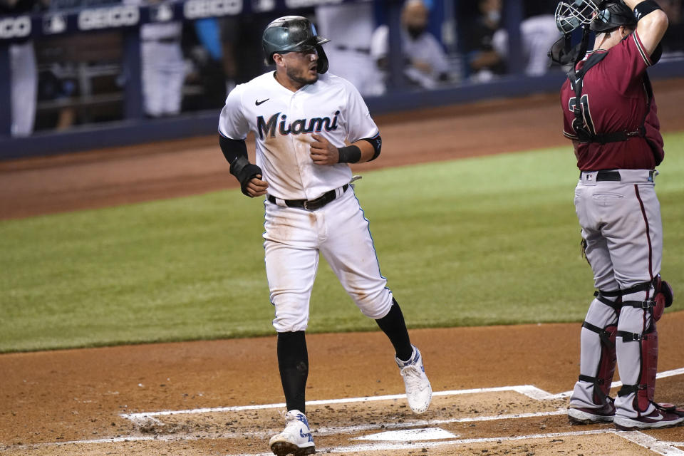 Miami Marlins' Miguel Rojas, left scores past Arizona Diamondbacks catcher Stephen Vogt (21) on a single hit by Brian Anderson during the first inning of a baseball game, Wednesday, May 5, 2021, in Miami. (AP Photo/Lynne Sladky)