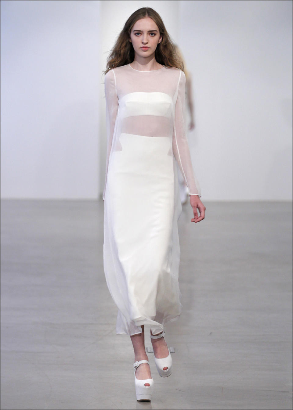 In this undated image released by Calvin Klein, a model wears a sheer ivory T-shirt over an ivory silk skirt and bandeau by Calvin Klein. True to form, the Calvin Klein resort collection is built on clean, architectural lines, but creative director Francisco Costa strategically inserts softer shapes _ and the occasional sexy cutout.(AP Photo/Calvin Klein)