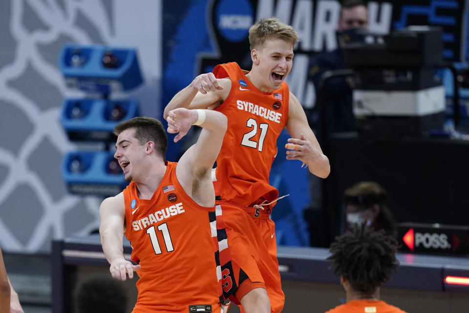 Syracuse's Joseph Girard III (11) and Marek Dolezaj (21) celebrate following a second-round game against West Virginia in the NCAA men's college basketball tournament at Bankers Life Fieldhouse, Sunday, March 21, 2021, in Indianapolis. Syracuse defeated Syracuse 75-72. (AP Photo/Darron Cummings)