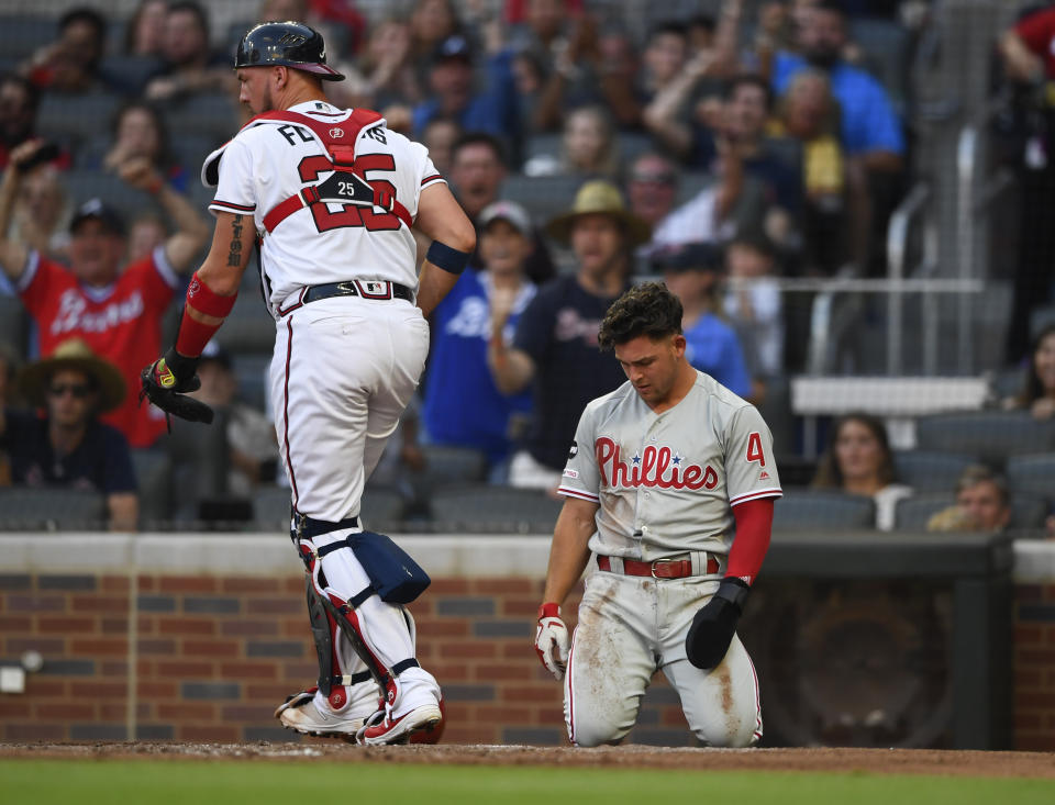 Philadelphia Phillies' Scott Kingery, right, kneels at the plate after getting caught stealing home by Atlanta Braves catcher Tyler Flowers, left, during the second inning of a baseball game Saturday, June 15, 2019, in Atlanta. (AP Photo/John Amis)