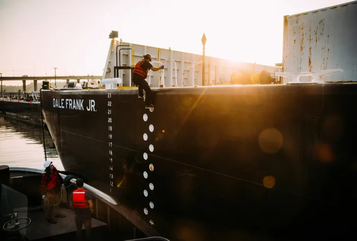 A crew member of the tugboat Millennium Falcon boards the tank barge Dale Frank Jr. in Seattle's Elliott Bay, Oct. 5, 2022. (Lindsey Wasson/The New York Times)