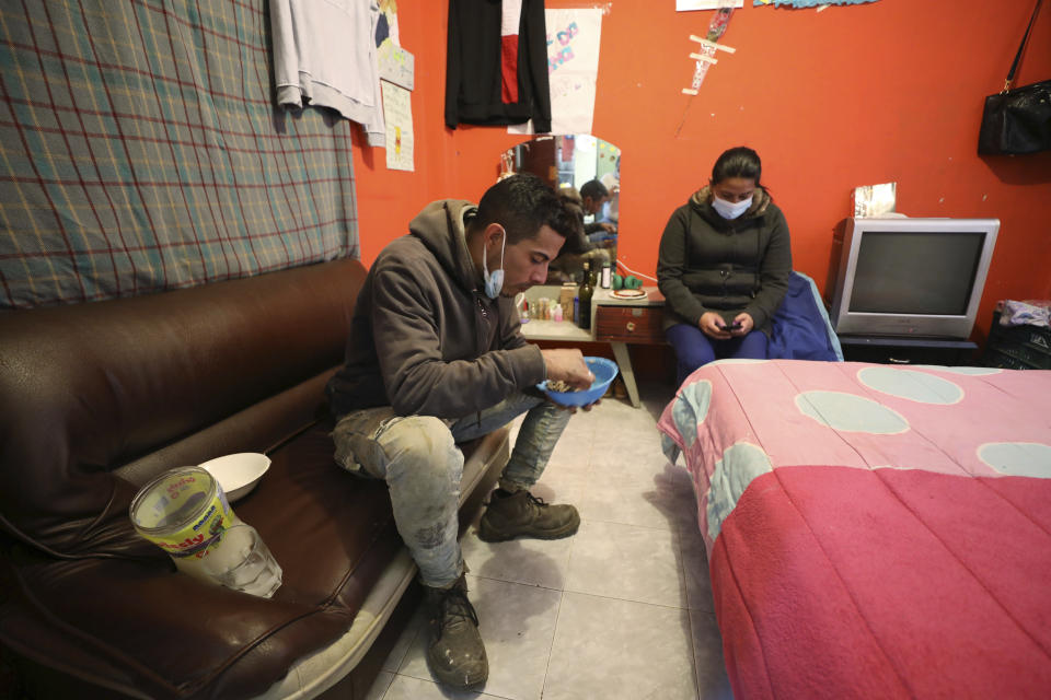 La migrante venezolana Yaquelin Timaure está acompañada de su pareja, Ricardo Luzardo, mientras come en su casa en Bogotá, Colombia, el lunes 21 de diciembre de 2020. (AP Foto/Fernando Vergara)