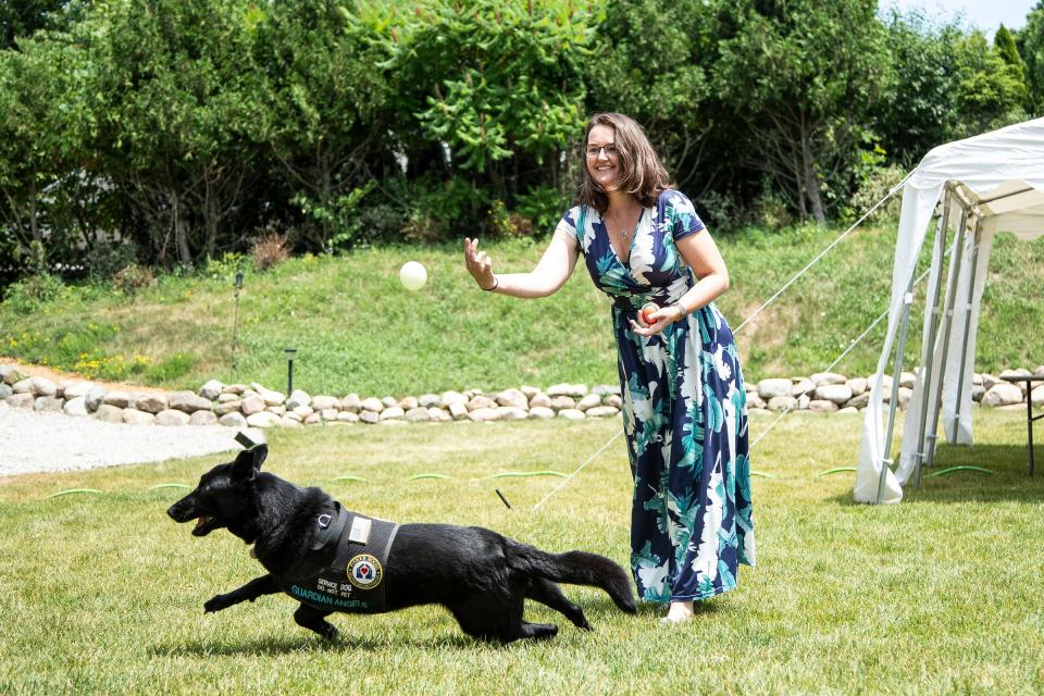 Army veteran Kate Melcher plays fetch with her Guardian Angel service dog Cat in Ann Arbor on June 30, 2022.