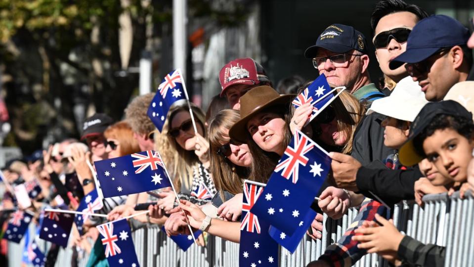 Spectators wave Australian flags during the Anzac Day March in Sydney