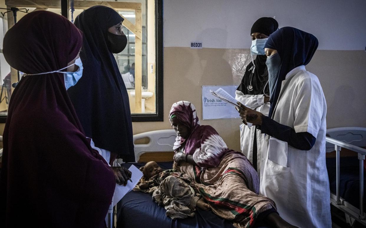 A baby lies with its mother while being treated for severe acute malnutrition