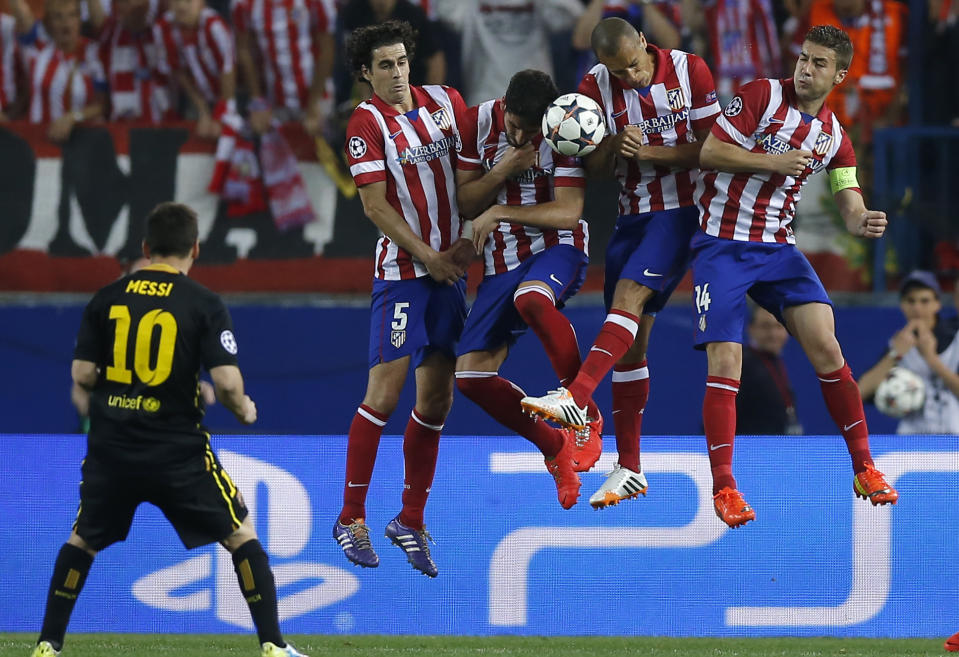 Barcelona's Lionel Messi kicks the ball in front of Atletico players during the Champions League quarterfinal second leg soccer match between Atletico Madrid and FC Barcelona at the Vicente Calderon stadium in Madrid, Spain, Wednesday, April 9, 2014. (AP Photo/Andres Kudacki)