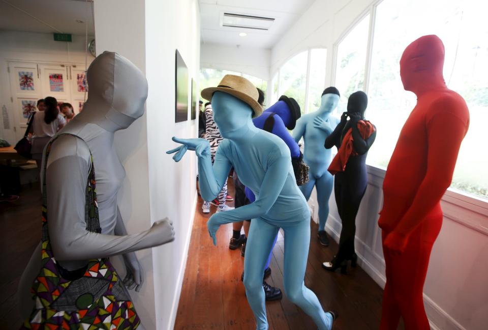 Participants wearing Zentai costumes mingle before their march down the shopping district of Orchard Road during Zentai Art Festival in Singapore