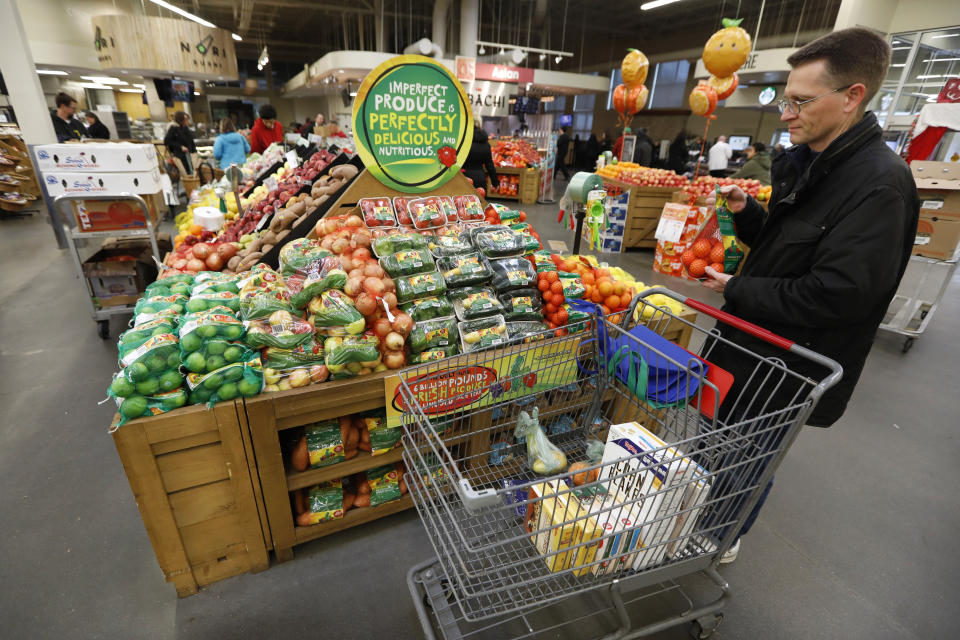 In this Friday, Jan. 18, 2019, photo, Brian Tice, of Urbandale, Iowa, looks at the imperfect produce display at the Hy-Vee grocery store in Urbandale, Iowa. “I like the cost savings and it is good to help and not throw so much away,” said Tice, who bought a pack of small oranges. (AP Photo/Charlie Neibergall)