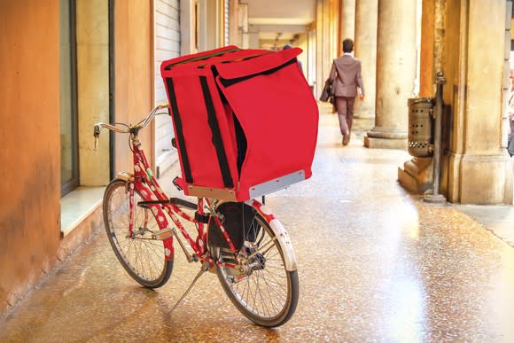 A delivery bike sits in the hallway of an office building.