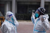 FILE PHOTO: Pandemic prevention workers in protective suits get ready to enter an apartment building that went into lockdown as coronavirus disease (COVID-19) outbreaks continue in Beijing