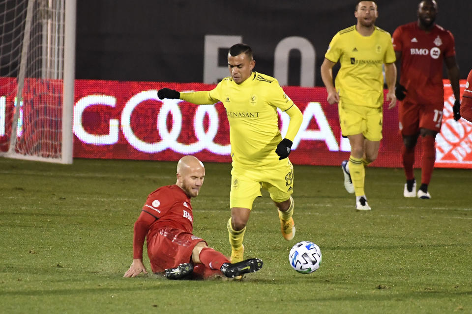 Nashville SC's Randall Leal, right front, trips over the foot of Toronto FC's Michael Bradley during the first half of an MLS soccer playoff match Tuesday, Nov. 24, 2020, in East Hartford, Conn. (AP Photo/Jessica Hill)