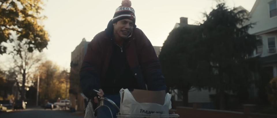 Pete Davidson wearing a hat and riding a bike in "Dumb Money."