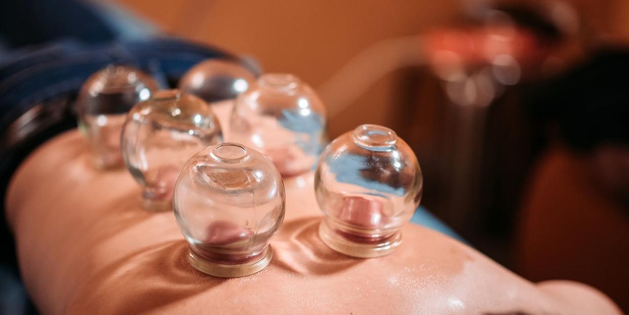 asian chinese male patient receiving cupping therapy treatment at chinese medicine shop