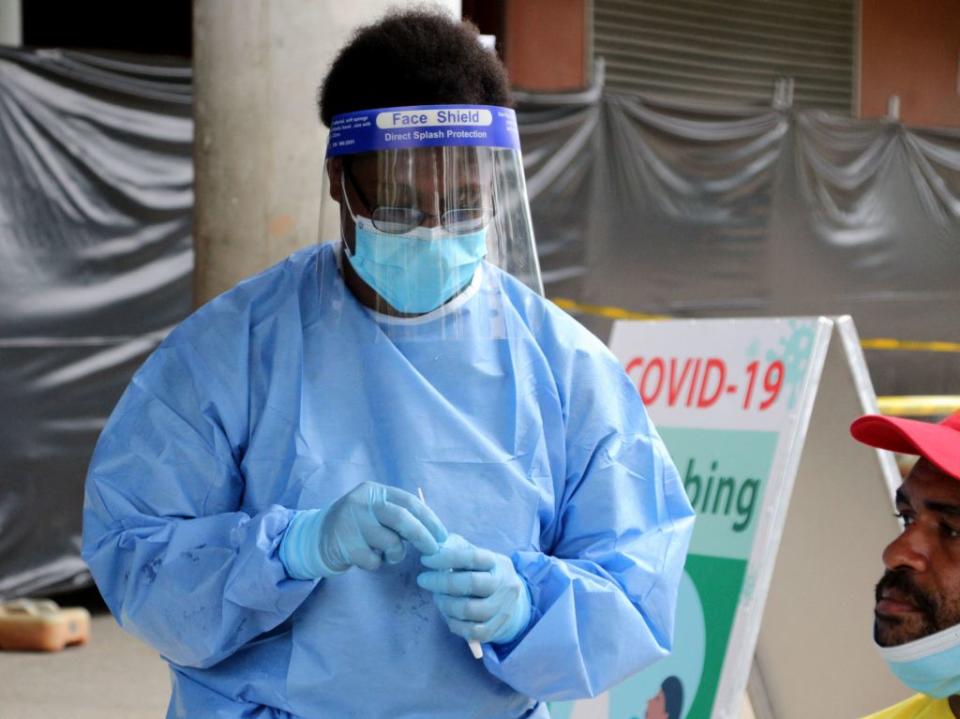 A health worker prepares to take a swab from a man to test for Covid-19 coronavirus outside a makeshift clinic in a sports stadium in Port Moresby.