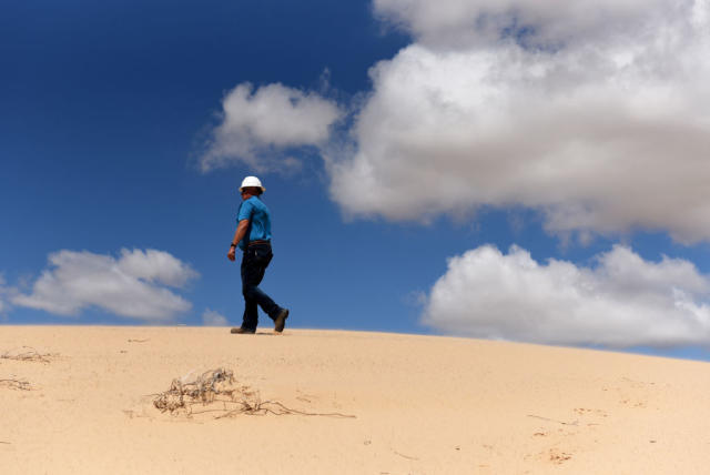 A worker walks along a sand dune at the Hi-Crush Partners LP mining facility in Kermit, Texas, U.S., on Wednesday, June 20, 2018. In the West Texas plains, frack-sand mines suddenly seem to be popping up everywhere. Twelve months ago, none of them existed - together, these mines will ship some 22 million tons of sand this year to shale drillers in the Permian Basin, the hottest oil patch on Earth. Photographer: Callaghan O'Hare/Bloomberg