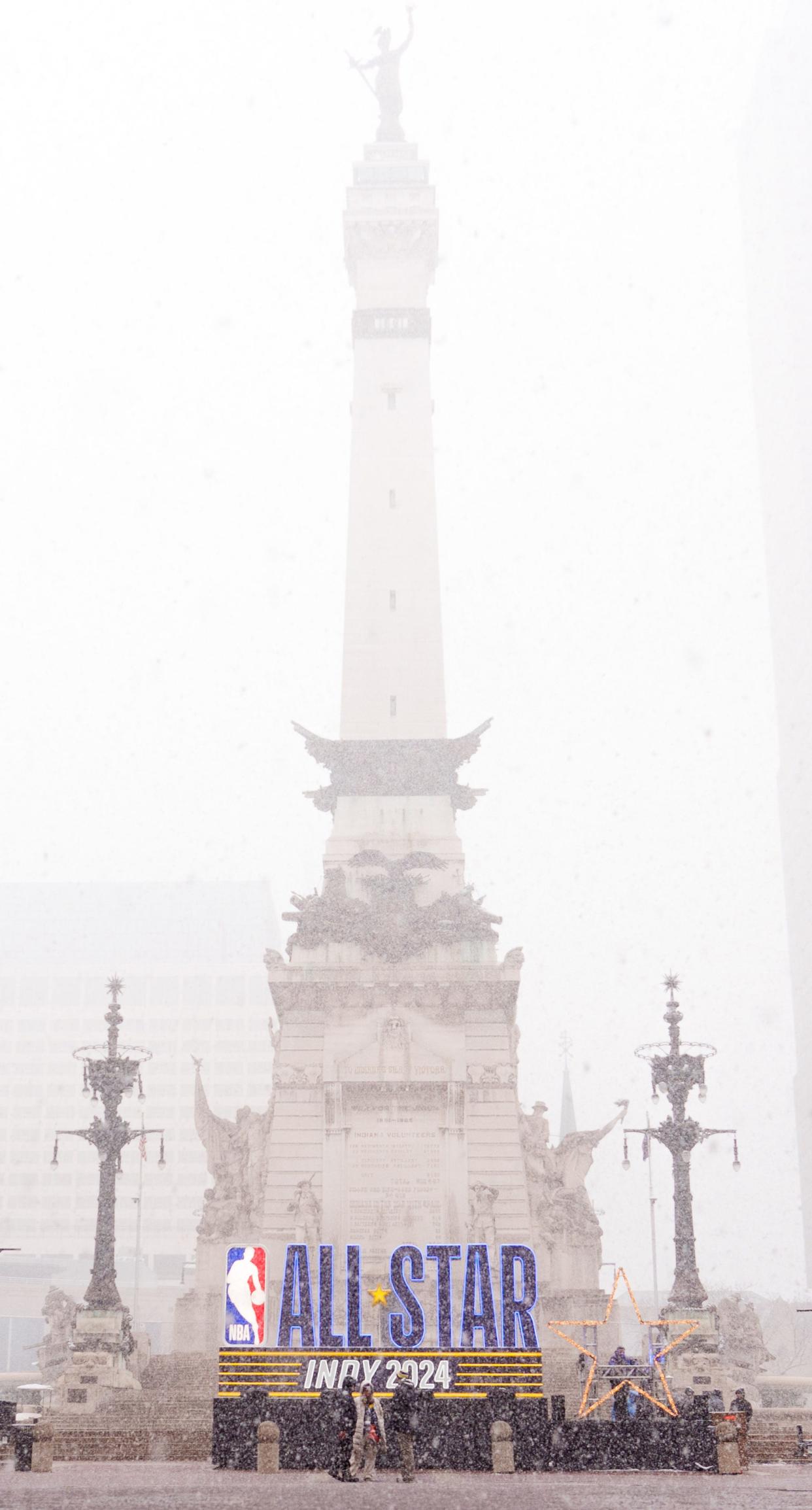 Snow falls Friday, Feb. 16, 2024, in front of an NBA All-Star Indy 2024 sign on Monument Circle in Indianapolis.