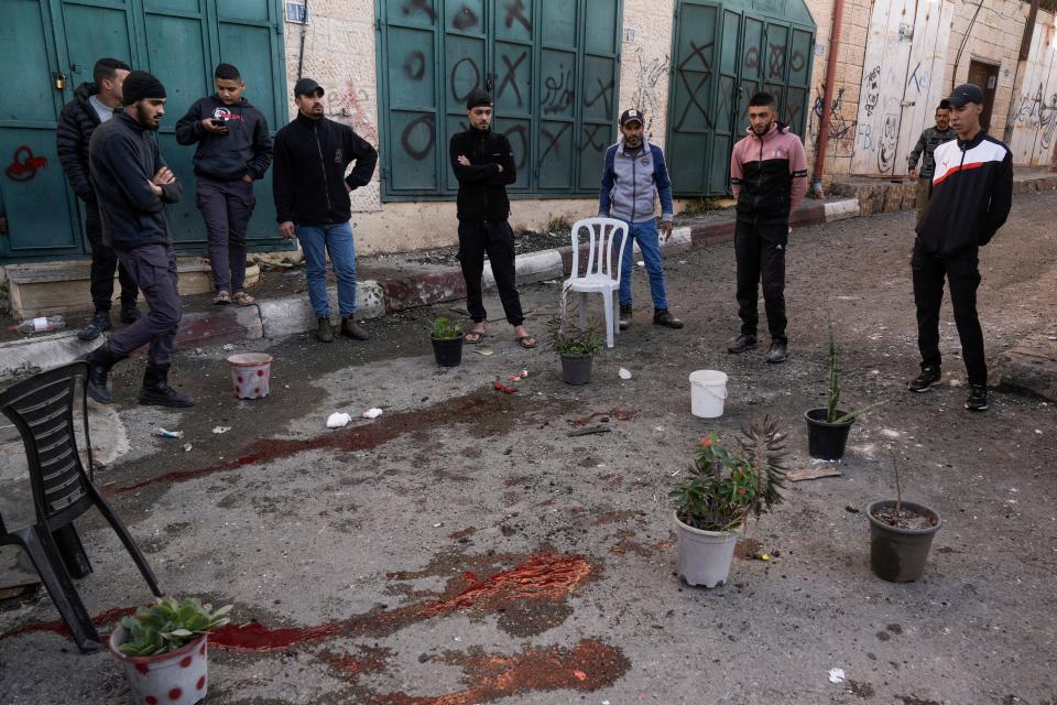 Palestinians look at a blood stain at the site of the Israeli army operation, in the Jenin refugee camp in West Bank, Tuesday, Dec. 12, 2023.