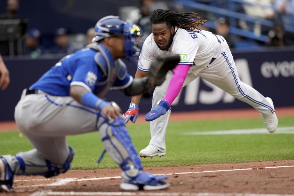 Toronto Blue Jays' Vladimir Guerrero Jr. (27) dives into home plate to score a run as Kansas City Royals catcher Salvador Perez (13) waits for the throw during the sixth inning of a baseball game in Toronto, Saturday, Sept. 9, 2023. (Nathan Denette/The Canadian Press via AP)