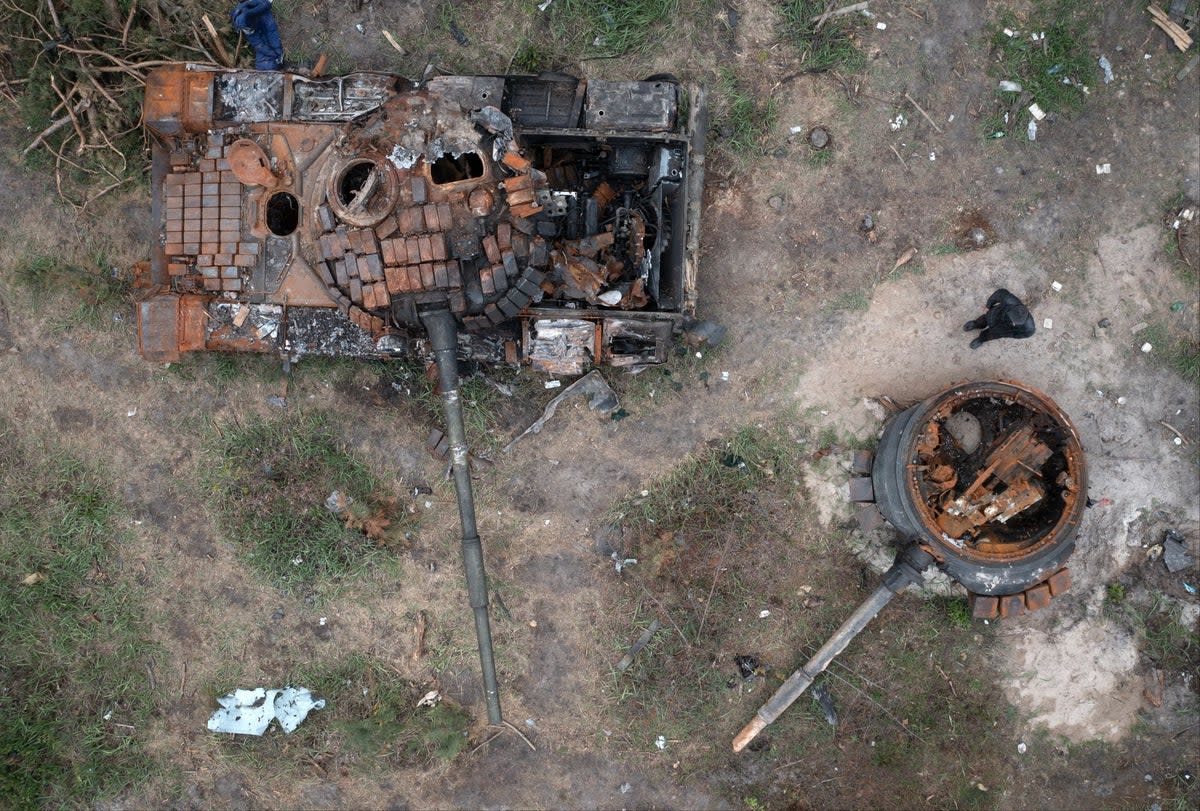 A man passes by Russian tanks destroyed in a recent battle against Ukrainians in the village of Dmytrivka (AP)