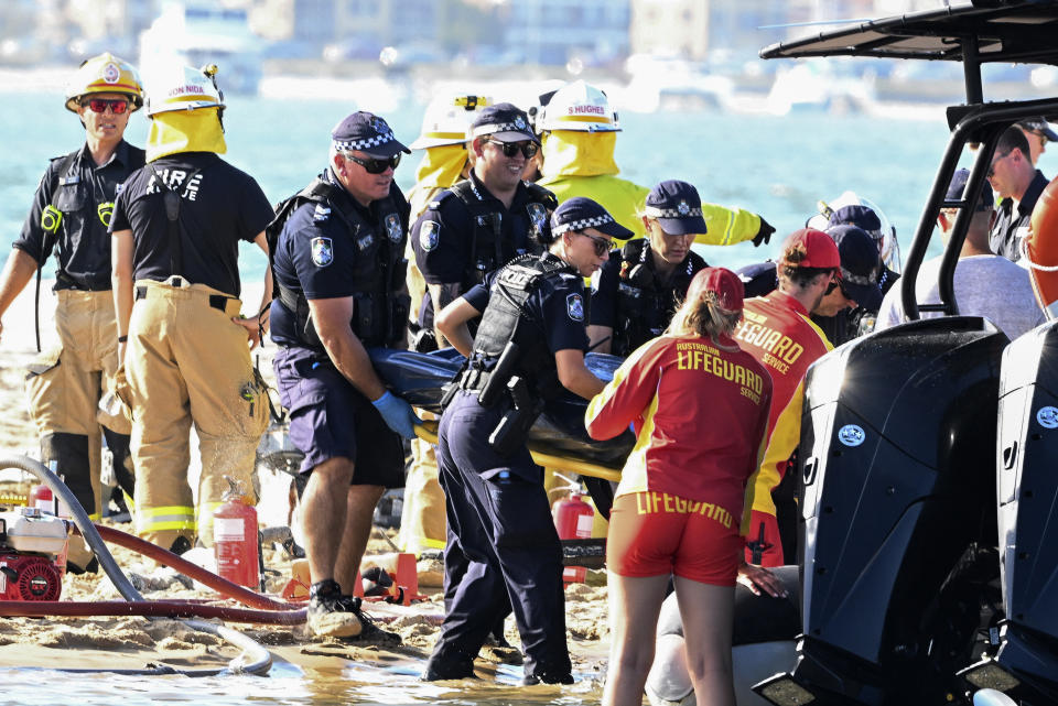 Emergency workers remove a body from a helicopter collision scene near Seaworld, on the Gold Coast, Australia, Monday, Jan. 2, 2023. Two helicopters collided killing several passengers and critically injuring a few others in a crash that drew emergency aid from beachgoers enjoying the water during the southern summer. (Dave Hunt/AAP Image via AP)