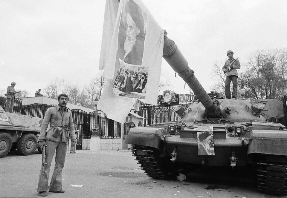 FILE - In this Feb. 13, 1979 file photo, a large picture of Ayatollah Khomeini hangs from tank gun barrel in front of Niavaran Palace in Tehran, Iran. Monday, Feb. 11, 2019 marks the 40th anniversary of the Islamic Revolution in Iran, which overthrew the caretaker government left behind by the cancer-stricken Shah Mohammad Reza Pahlavi, who had left the country only weeks earlier. (AP Photo/Aristotle Saris, File)