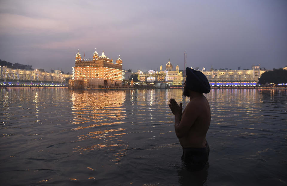 FILE - An Indian Sikh offers prayers as he takes a holy dip at the Golden Temple illuminated on the birth anniversary of Guru Nanak in Amritsar, India, on Nov. 12, 2019. A man was beaten to death in the northern Indian city of Amritsar after he allegedly attempted to commit a sacrilegious act inside the historic Golden Temple, one of Sikhism’s most revered shrines. The incident occurred on Saturday, Dec. 18, 2021, during the daily evening prayer, local media reported. (AP Photo/Prabhjot Gill, File)