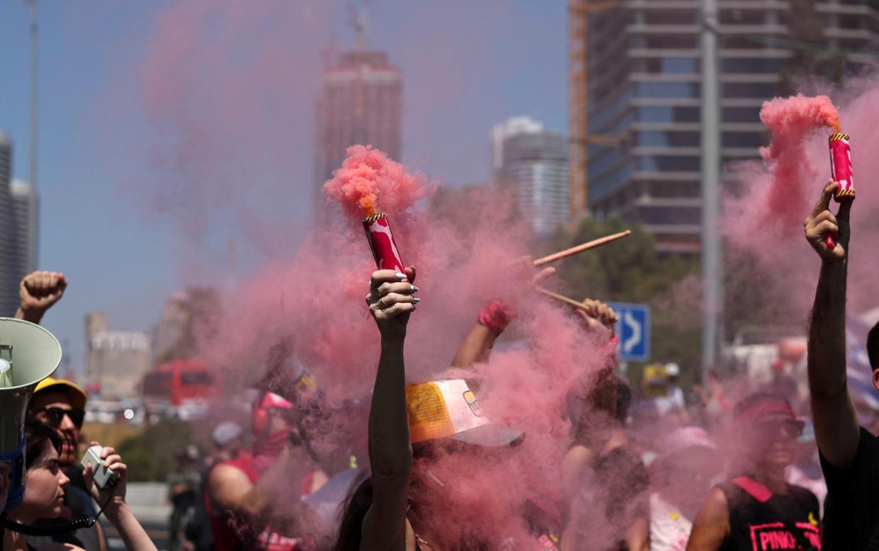 Israeli protesters light up smoke bombs as they block a road during an Israeli hostages families' protest in Tel Aviv