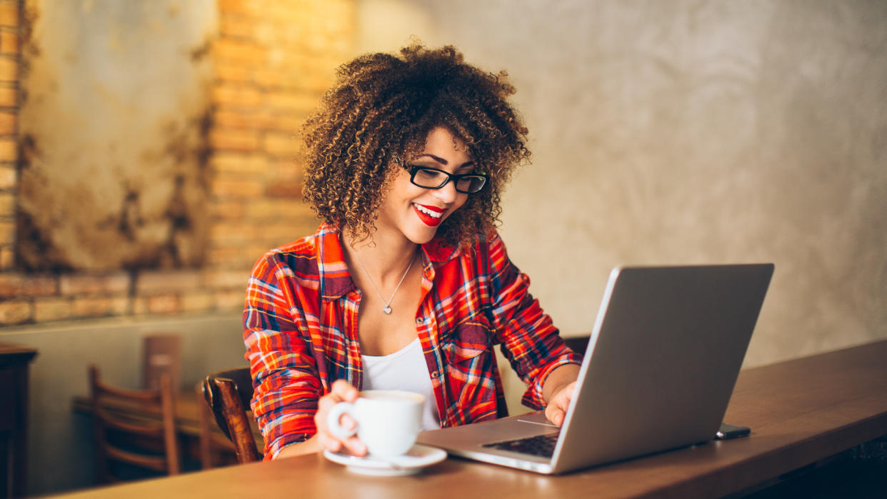 Young woman siting at cafe drinking coffee and working on laptop.