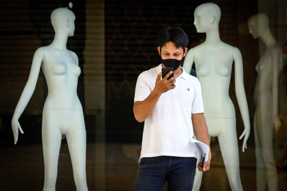 A man looks at his mobile phone in a partially closed shopping mall preparing to fully re-open when the Thai government further relaxes measures to combat the spread of the COVID-19 novel coronavirus in Bangkok on May 11, 2020. (Photo by Mladen ANTONOV / AFP) (Photo by MLADEN ANTONOV/AFP via Getty Images)