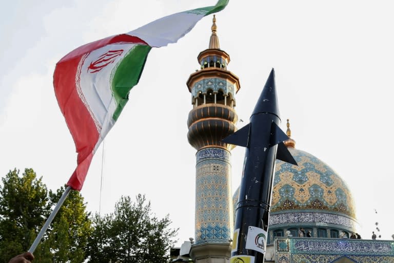 Des Iraniens brandissent un drapeau et la maquette d'un missile après après l'attaque de missiles et de drones iraniens contre Israël, le 15 avril 2024, dans le centre de Téhéran. (ATTA KENARE)