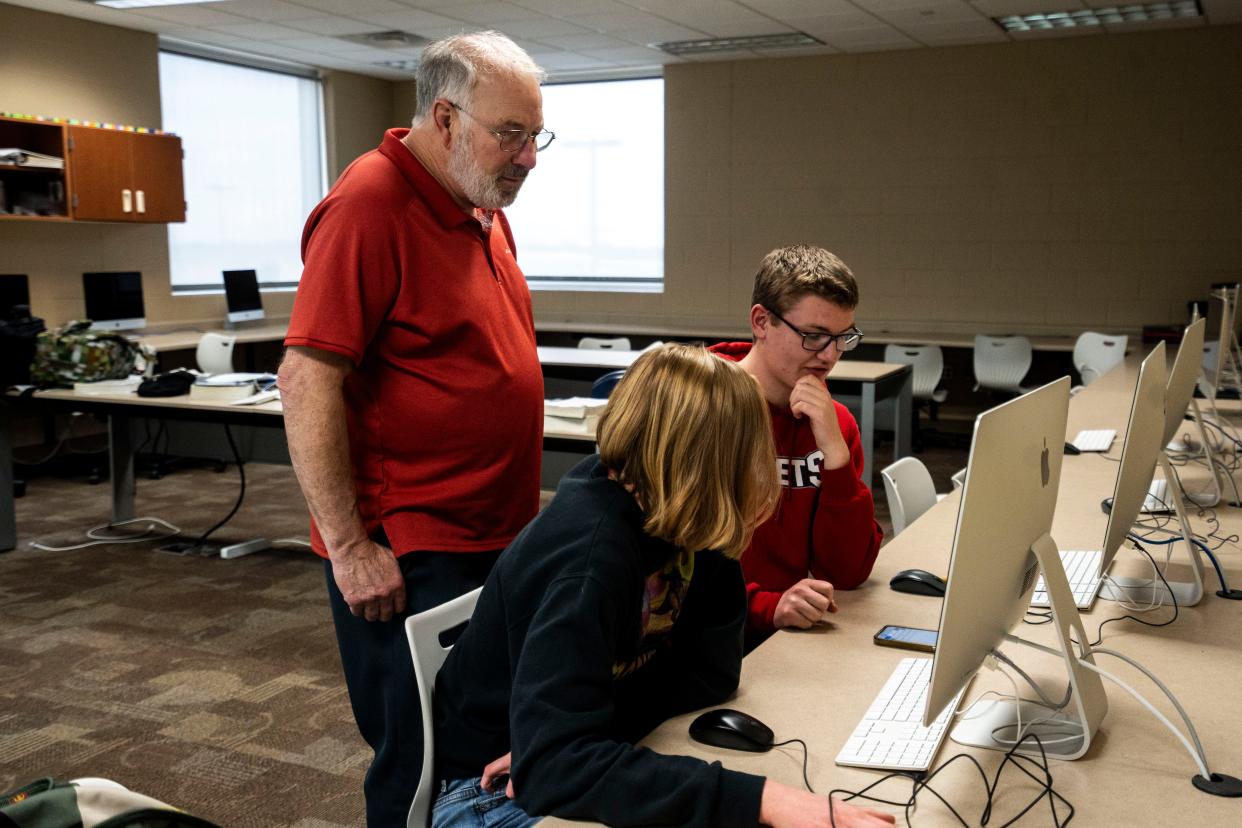 North Polk High School teacher Bruce Bennett assists students during his last class of the day.