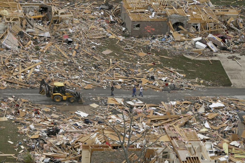 People walk between two destroyed houses in Mayflower, Ark., Monday, April 28, 2014, after a tornado struck the town late Sunday. A tornado system ripped through several states in the central U.S. and left at least 17 dead in a violent start to this year's storm season, officials said. (AP Photo/Danny Johnston)