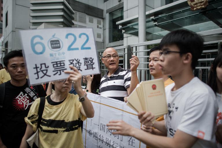 A demonstrator supporting the "occupy central" movement holds a placard asking residents to cast ballots for the June 22 referendum on three proposals outlining rules for the chief executive election, in Hong Kong on June 11, 2014