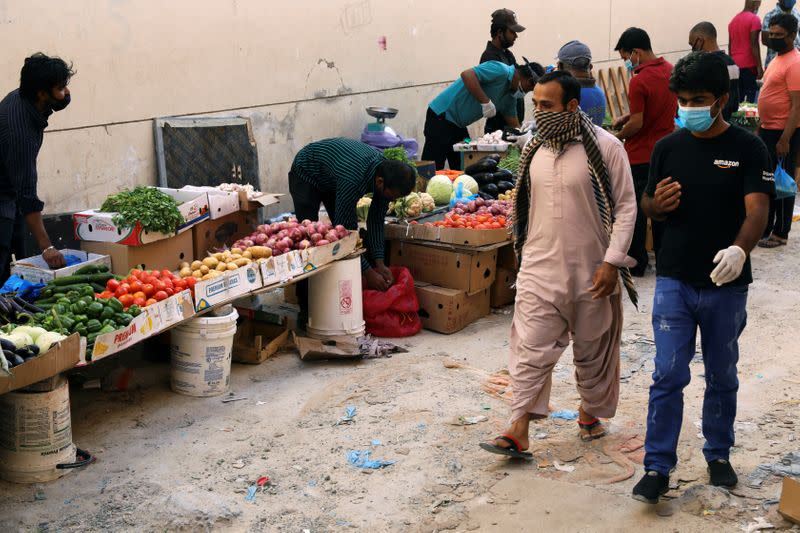 Foreign workers wearing protective face masks walk through a street market, following the outbreak of the coronavirus disease (COVID-19), in the Al Quoz industrial district of Dubai