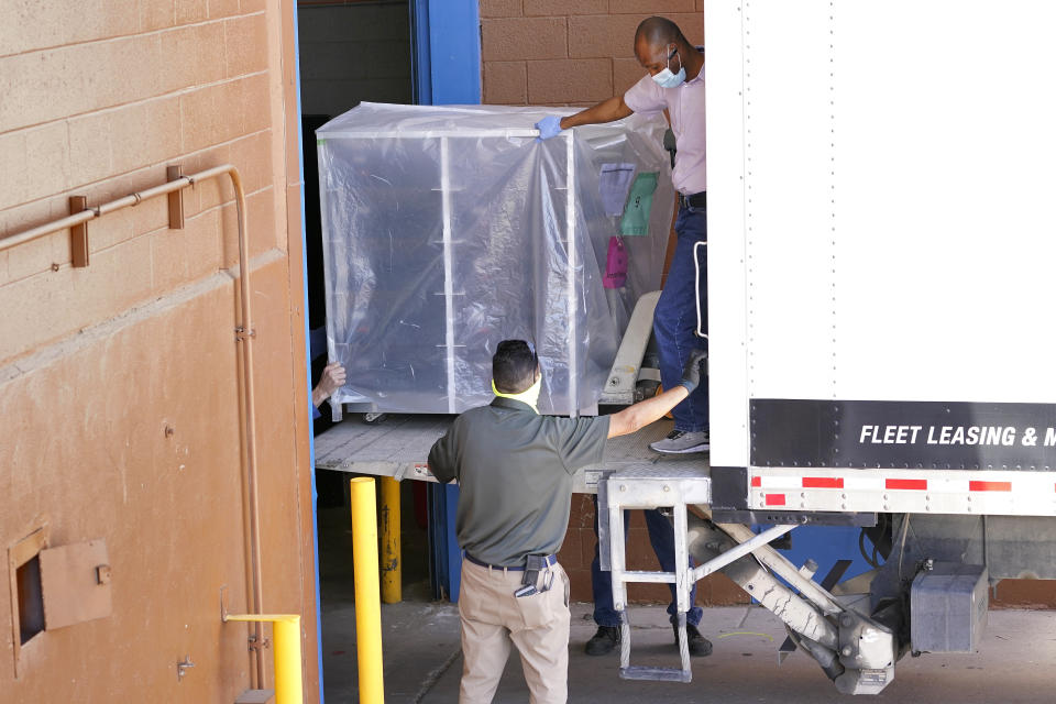 FILE - In this April 21, 2021 file photo, officials unload election equipment into the Veterans Memorial Coliseum at the state fairgrounds in Phoenix. Arizona’s largest county has approved nearly $3 million for new vote-counting machines to replace those given to legislative Republicans for a partisan review of the 2020 election. The GOP-controlled Maricopa County Board of Supervisors said Wednesday, July 14, 2021 that the machines were compromised because they were in the control of firms not accredited to handle election equipment. (AP Photo/Matt York, File)