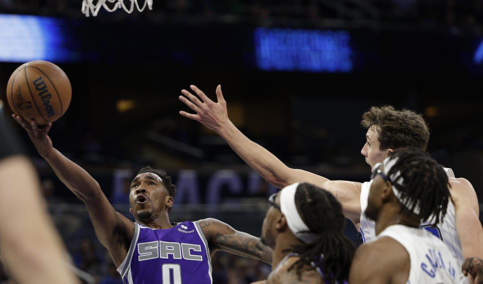 Sacramento Kings guard Malik Monk (0) shoot around a host of Orlando Magic players during the first half of an NBA basketball game, Saturday, Nov. 5, 2022, in Orlando, Fla. (AP Photo/Kevin Kolczynski)