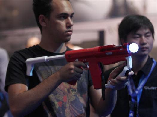 Visitors play a Playstation at an exhibition stand during the Gamescom 2012 fair in Cologne August 15, 2012.