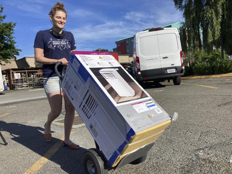 Sarah O'Sell transports her new air conditioning unit to her nearby apartment on a dolly in Seattle on Friday, June 25, 2021. O'Sell snagged one of the few AC units available at the Junction True Value Hardware as Pacific Northwest residents brace for an unprecedented heat wave that has temperatures forecasted in triple-digits. (AP Photo/Manuel Valdes)