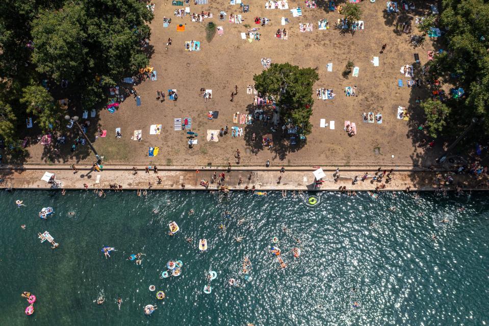Visitors swim and sunbathe at Barton Springs Pool on July 31. The pool has remained open, but that might change if water flow weakens.