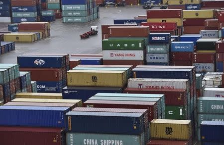 A transporter lorry drives between shipping containers stacked at the port of Felixstowe in south east England, January 7, 2015. REUTERS/Toby Melville