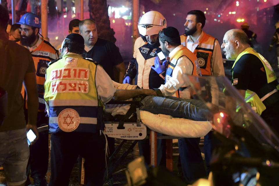 Israeli medics evacuate a wounded man after a rocket fired from the Gaza Strip hit the central Israeli town of Holon, near Tel Aviv, Tuesday, May 11, 2021. (AP Photo/Avshalom Sassoni)