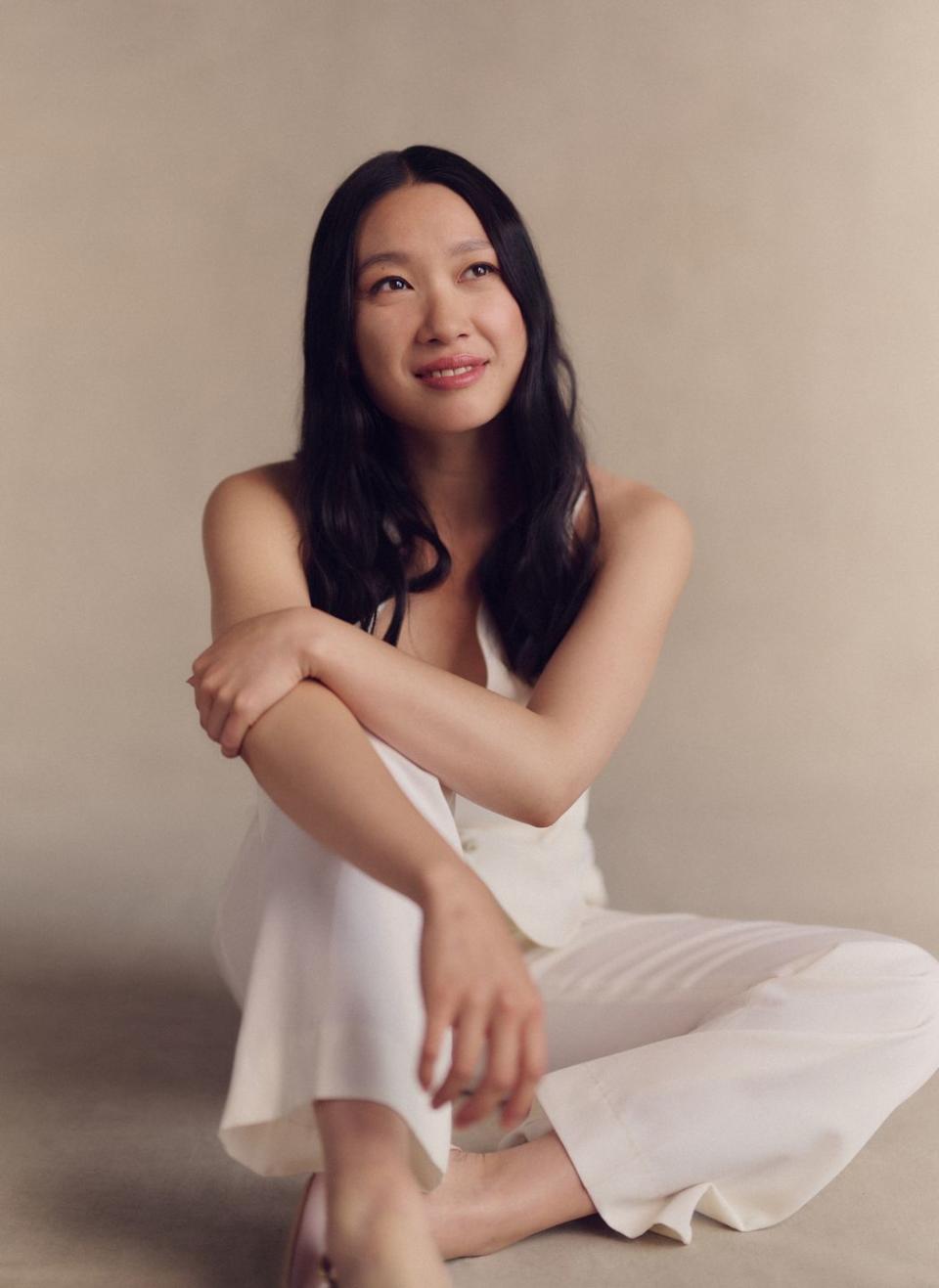 jess hong sitting on the floor in a white jumpsuit