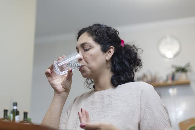 <p>Anderson Coelho / Getty Images</p> Female taking medication with water