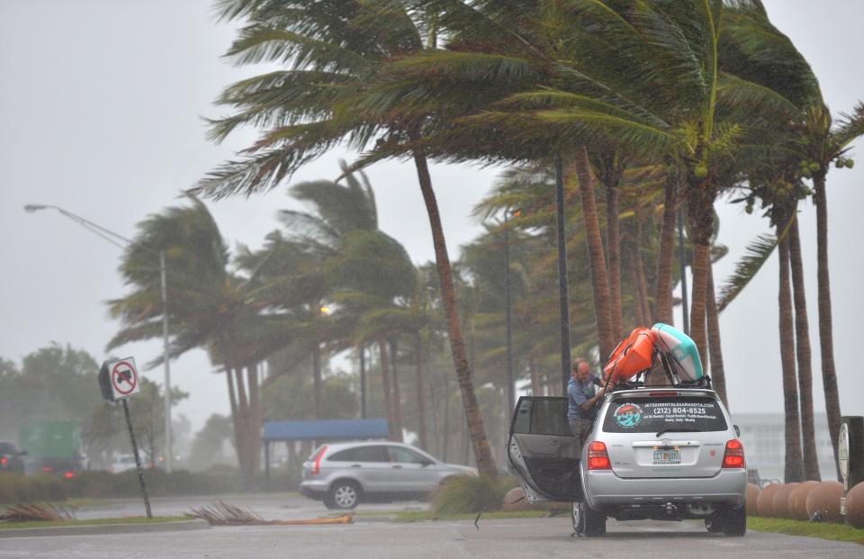 A driver secures a kayak as winds from Tropical Storm Nicole whip the palm trees at Bird Key Park along the John Ringling Causeway in Sarasota, Florida on Thursday, Nov. 10, 2022. 