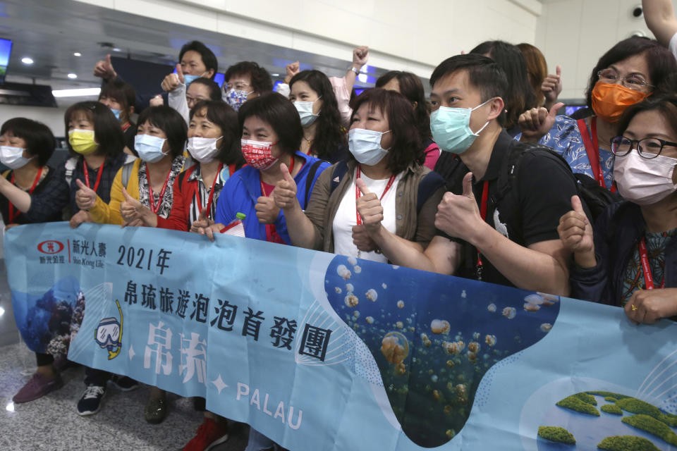 Taiwanese travelers of the first group of Palau-Taiwan Travel Corridor pose for a group photo before leaving Taiwan, at Taoyuan International Airport in Taoyuan, northern Taiwan, Thursday, April 1, 2021. The Palau-Taiwan Travel Corridor, allowing people to travel between the islands without a COVID-19 quarantine, has started Thursday. The banner reads: "First group of Palau-Taiwan Travel Corridor." (AP Photo/Chiang Ying-ying)