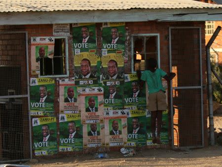 A boy plays next to election posters at White City Stadium where Zimbabwe's President Emmerson Mnangagwa escaped unhurt after an explosion rocked the stadium, in Bulawayo, Zimbabwe, June 23, 2018. REUTERS/Philimon Bulawayo